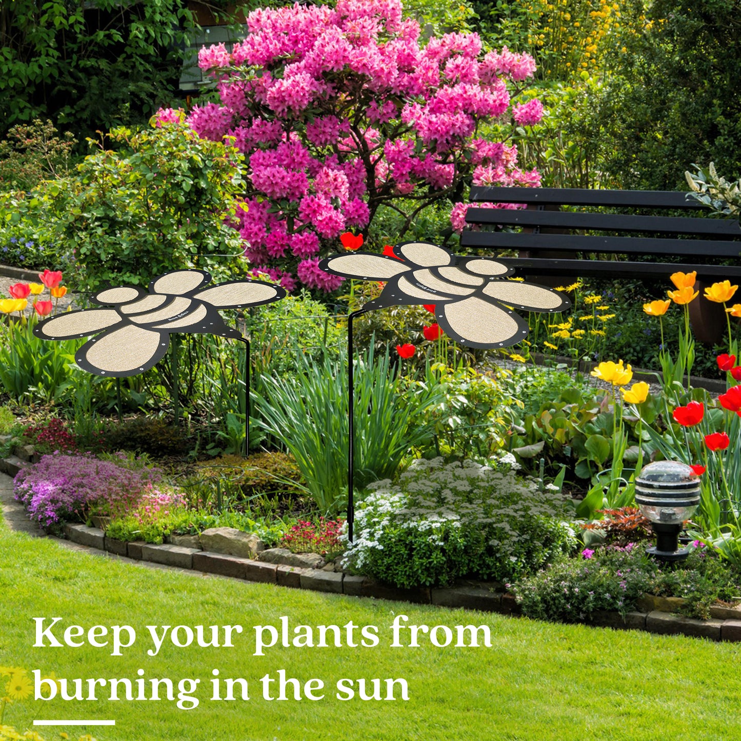 A vibrant garden features the Shade-A-Rella Super Sale! 24 inch Bee with black frame and light yellow 90% shade cloth—perfect for keeping your plants cool and protected from harsh sun, preventing burning.