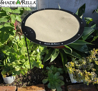 A Circle Shade-A-Rella adjustable plant umbrella by Shade-A-Rella is set up among green succulents in a garden, providing partial shade.