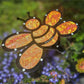 The Shade-A-Rella 10-inch small Bee with orange shimmer cloth, a 100% shade cloth holder Halloween bee, adds charm among purple flowers and greenery under a cute plant umbrella in your garden.