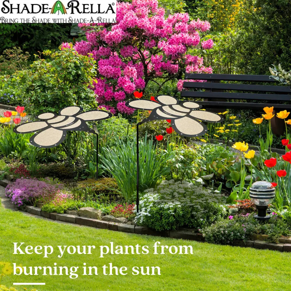 A vibrant garden features the Shade-A-Rella Super Sale! 24 inch Bee with black frame and light yellow 90% shade cloth—perfect for keeping your plants cool and protected from harsh sun, preventing burning.